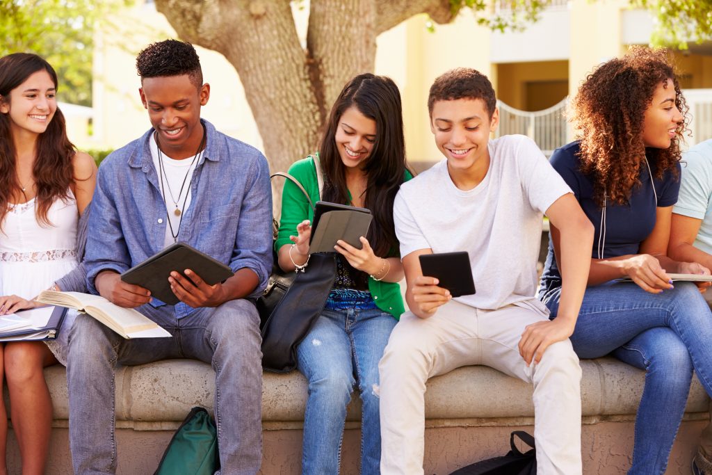 smiling teens using devices