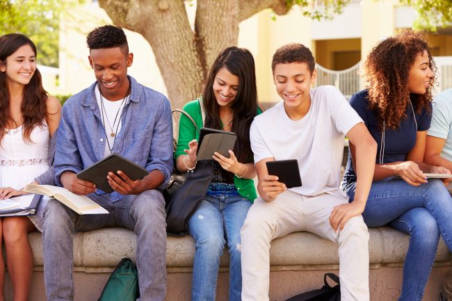 smiling teens using devices