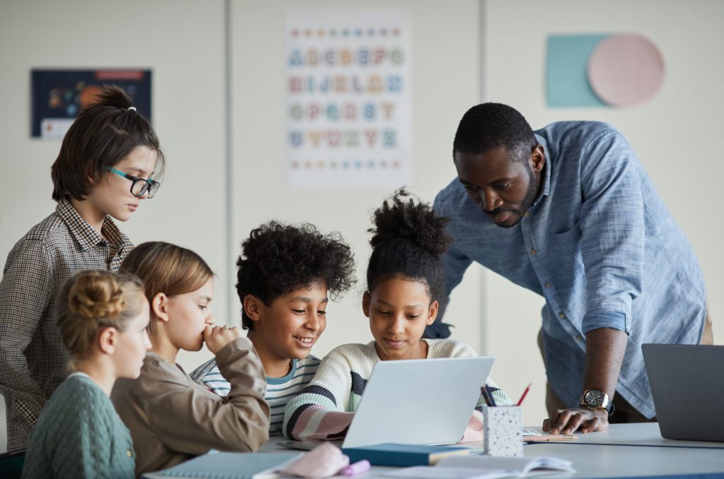 kids and teacher around computer