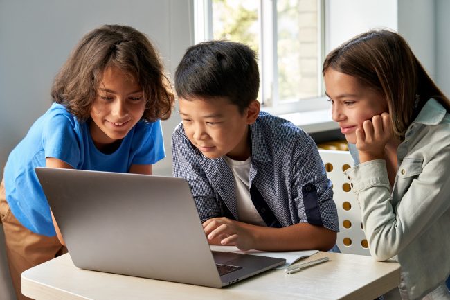 three kids around a computer